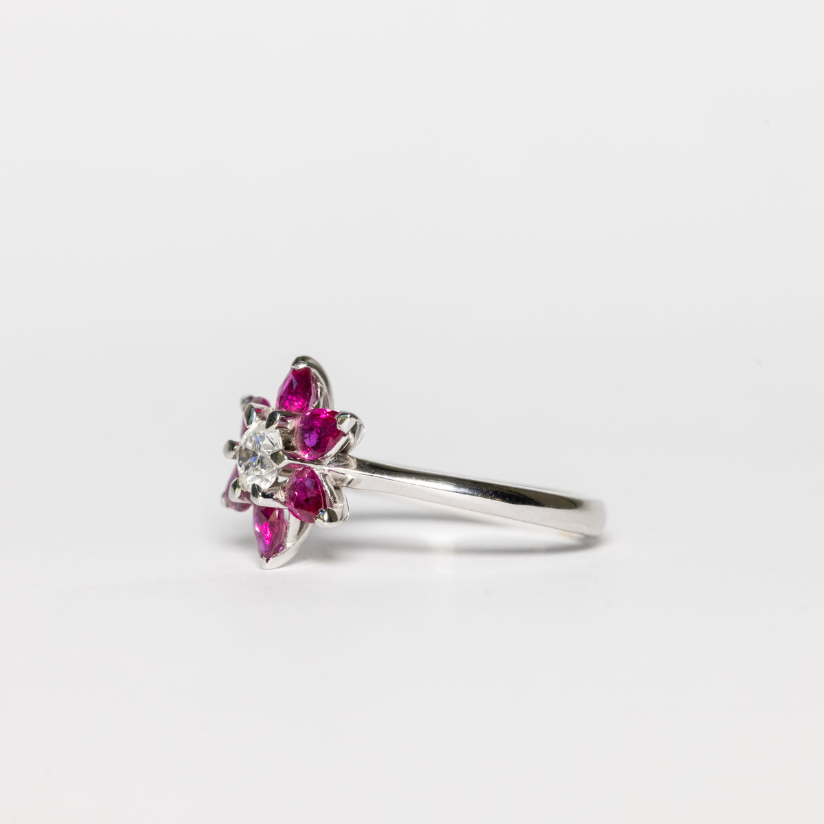 18kt white gold ring with ruby flower petals and 0.42 carat central diamond