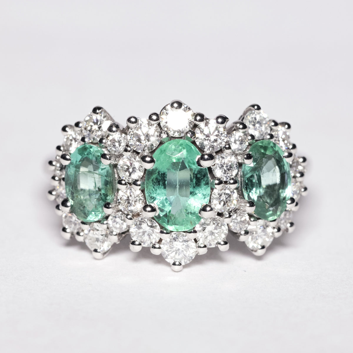 Trilogy ring with central emeralds and diamonds
