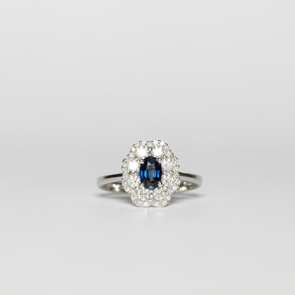 Anello in oro bianco 18 kt con zaffiro centrale forma ovale e contorno in diamanti