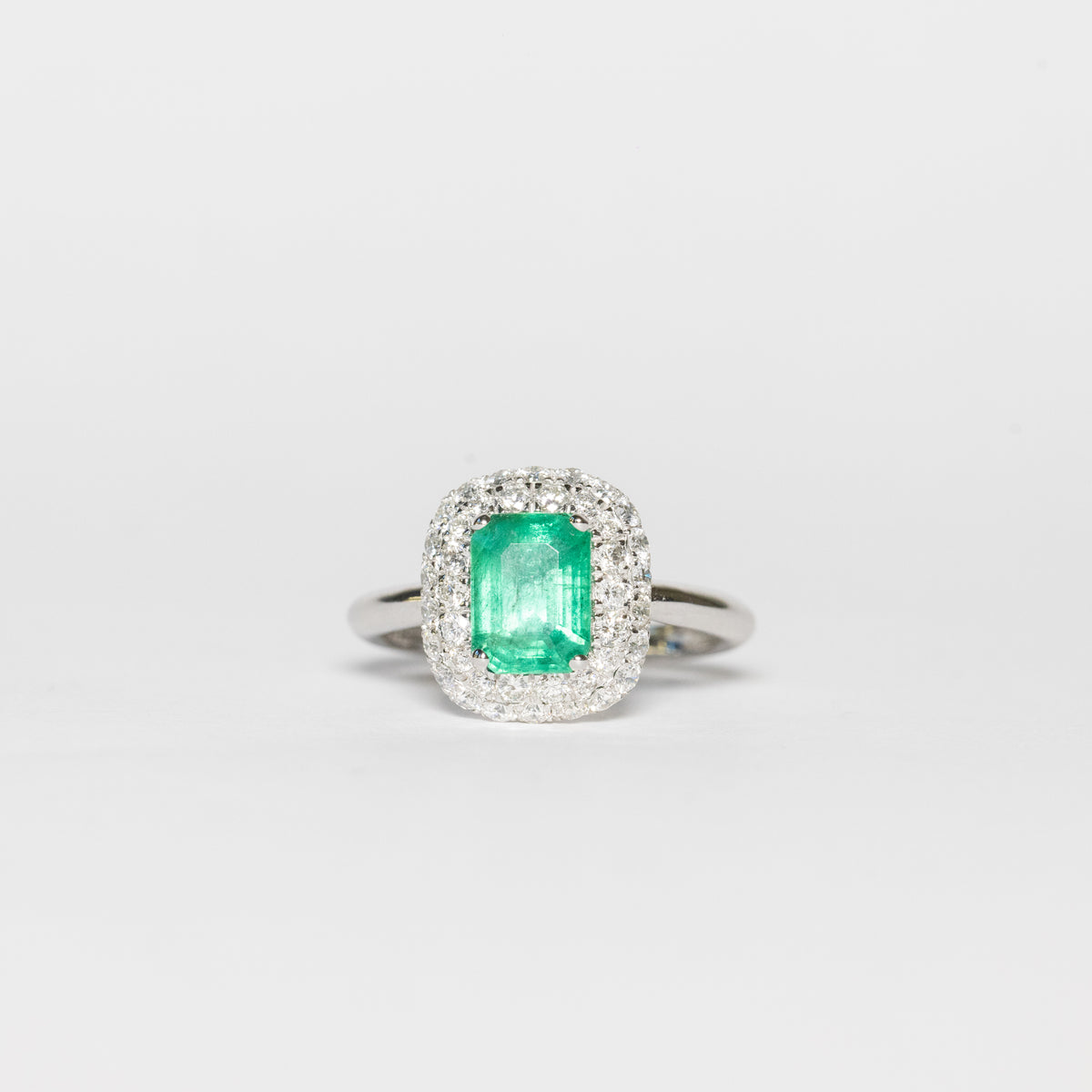 18kt white gold ring with central emerald and diamond surround