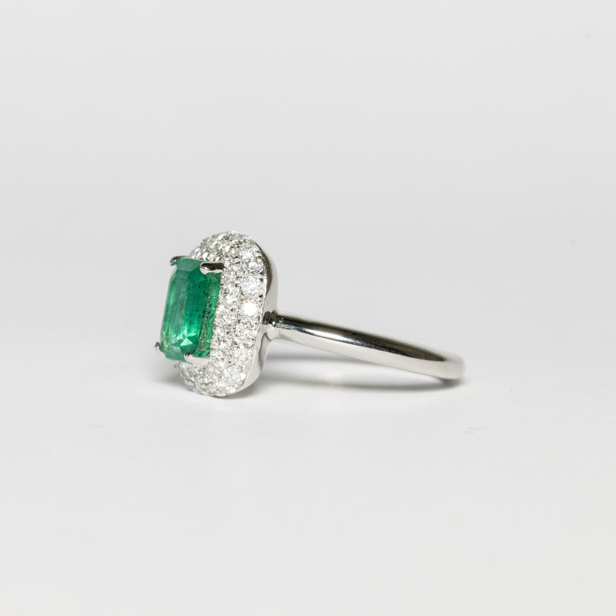 18kt white gold ring with central emerald and diamond surround