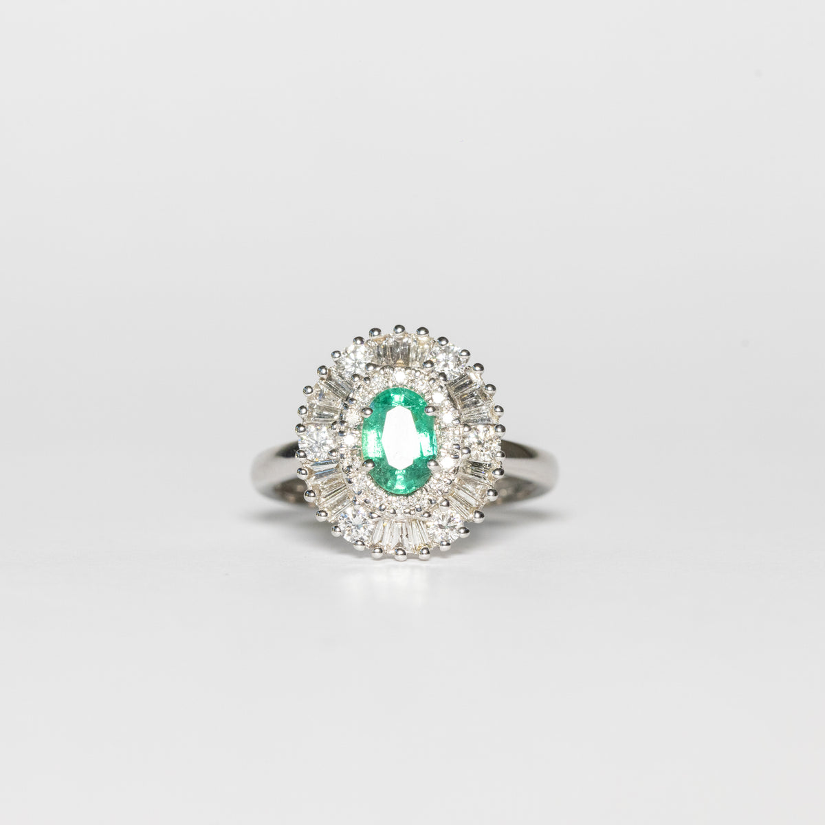 18kt white gold ring with central emerald and illusion diamond surround