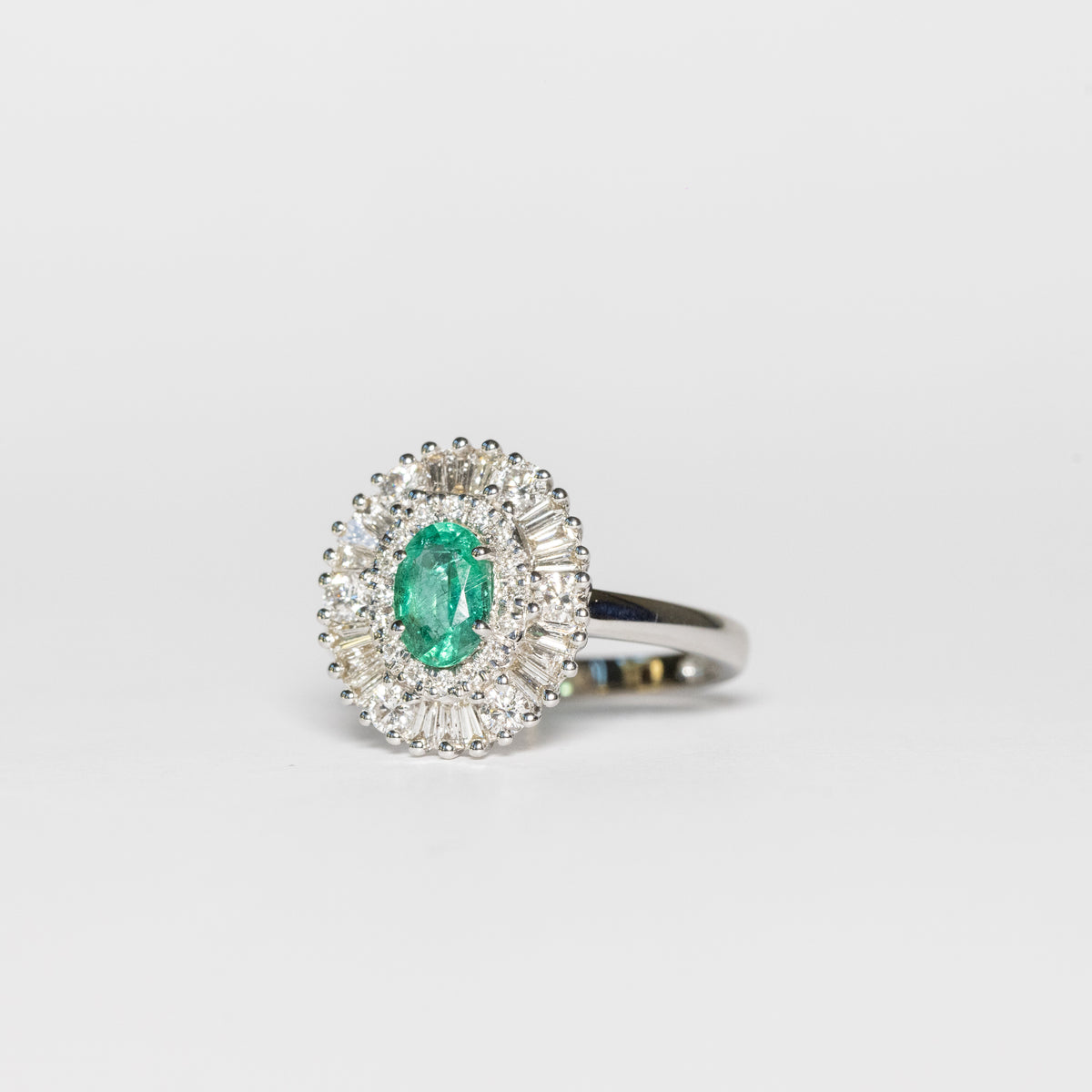 18kt white gold ring with central emerald and illusion diamond surround