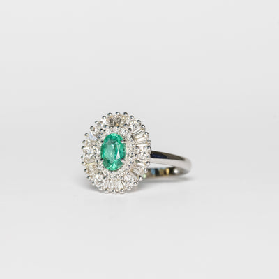 Anello in oro bianco 18kt con smeraldo centrale e contorno di diamanti illusion