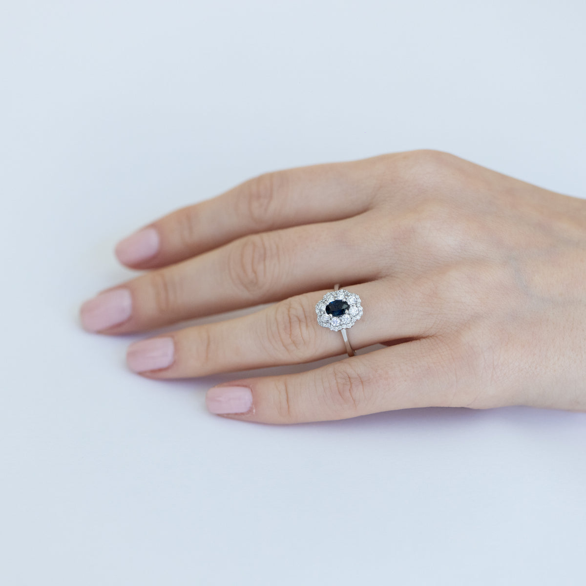 18kt white gold ring with oval-shaped central sapphire and diamond surround