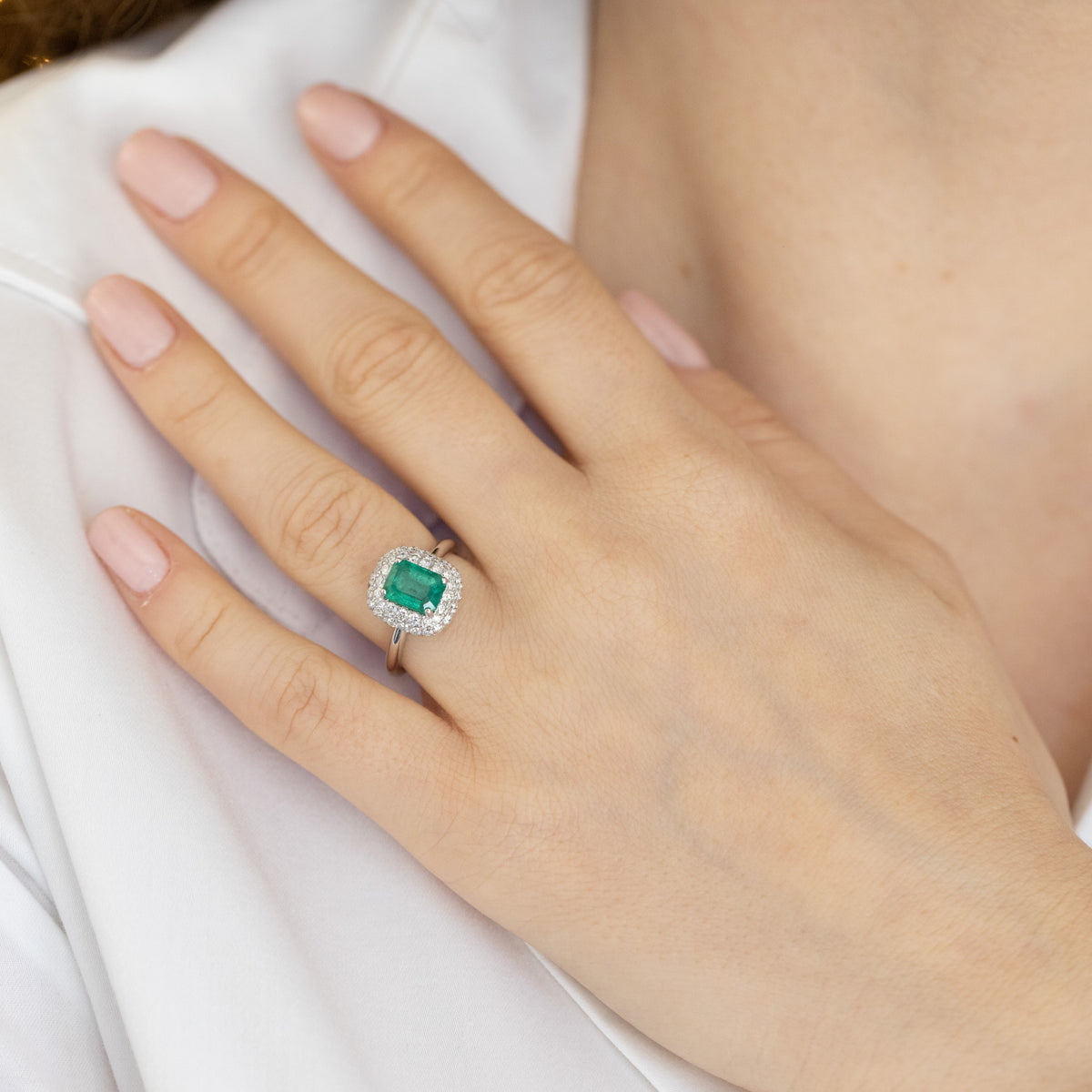 18kt white gold ring with central emerald and diamond surround