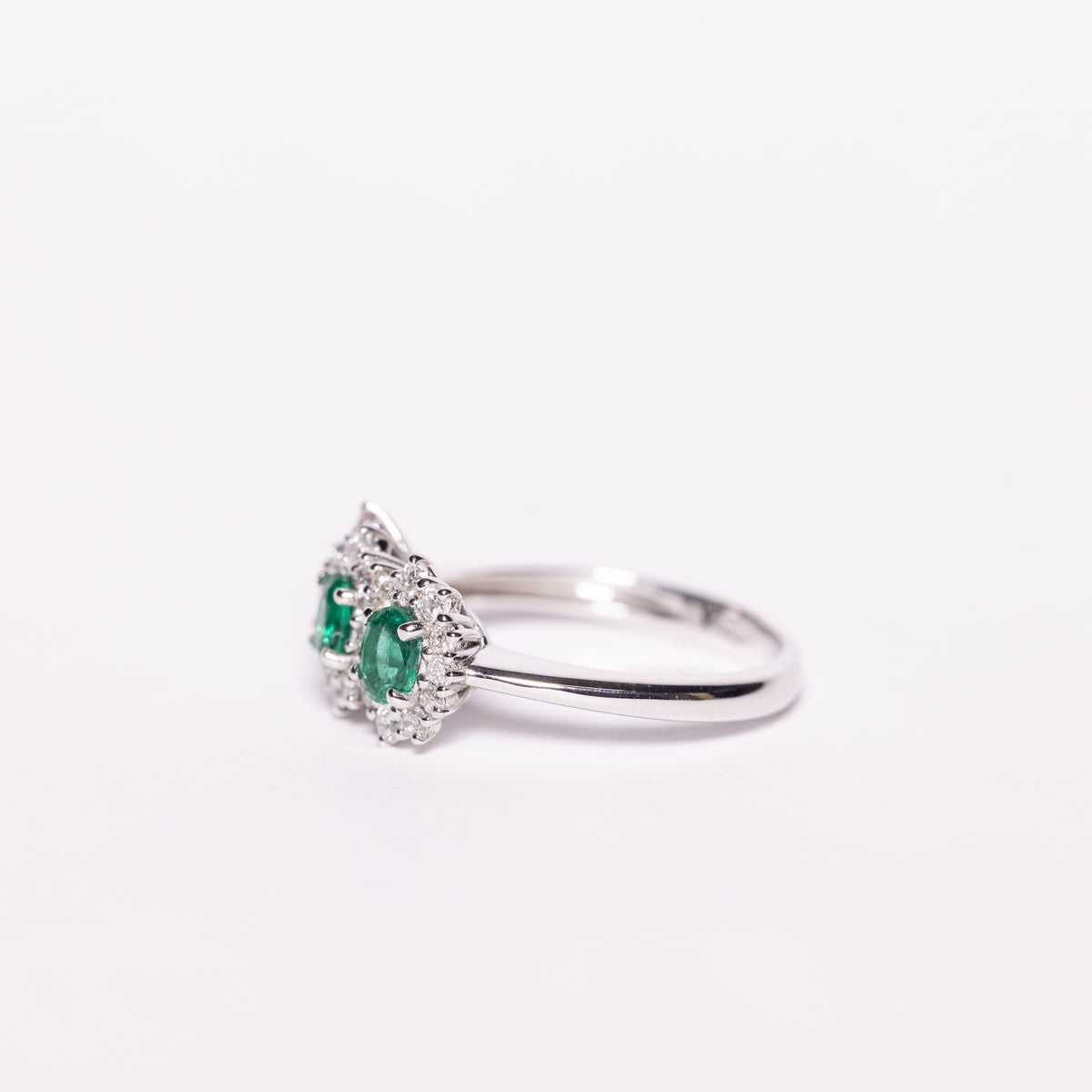18KT White Gold Trilogy Ring with Emeralds and Diamond Surround