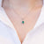 18kt white gold necklace with central emerald and diamond surround