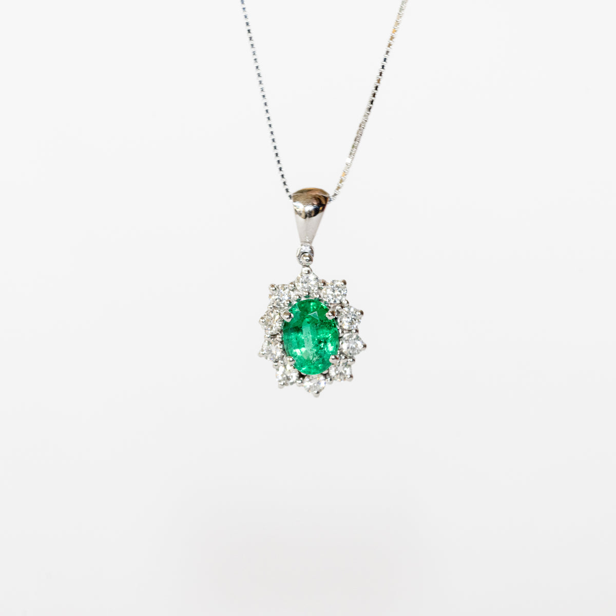 18kt white gold necklace with central emerald and diamond surround