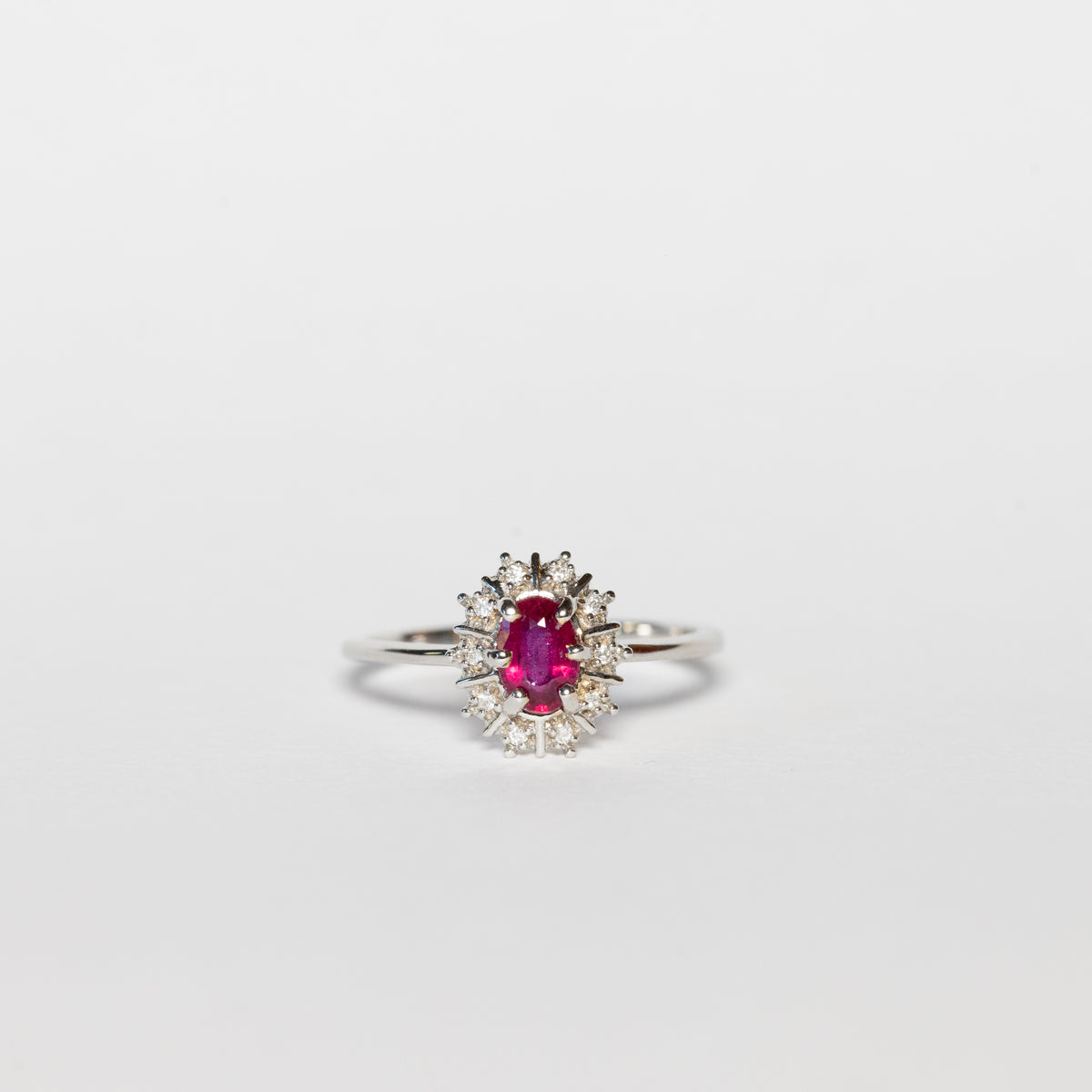 Anello in oro bianco 18 kt con rubino ovale e giro di diamanti
