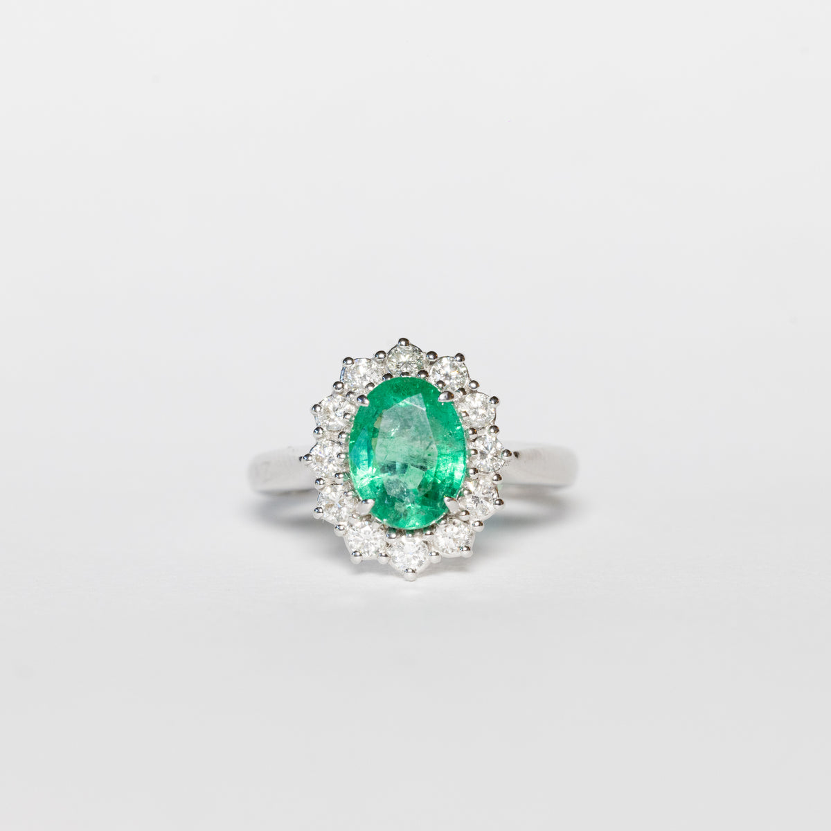 Anello in oro bianco 18 kt con smeraldo ovale e giro di diamanti