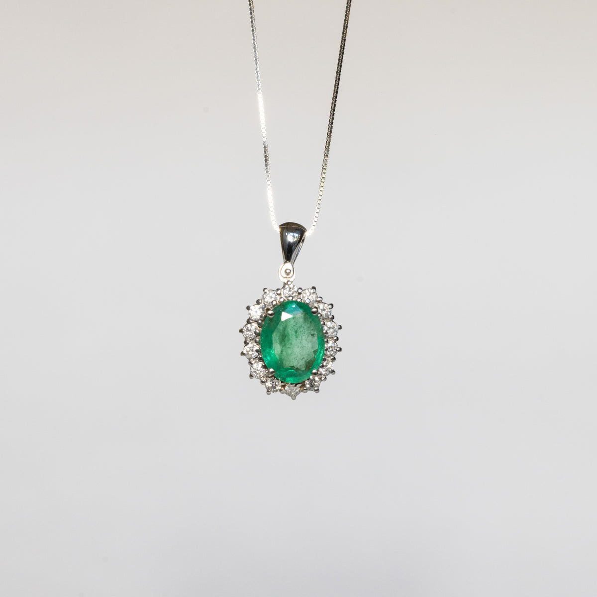 Collana in oro bianco 18 kt con smeraldo ovale e contorno di diamanti