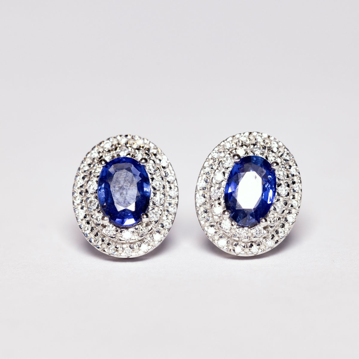 18KT WHITE GOLD EARRINGS WITH OVAL CUT SAPPHIRE WITH DOUBLE DIAMOND CONTOUR