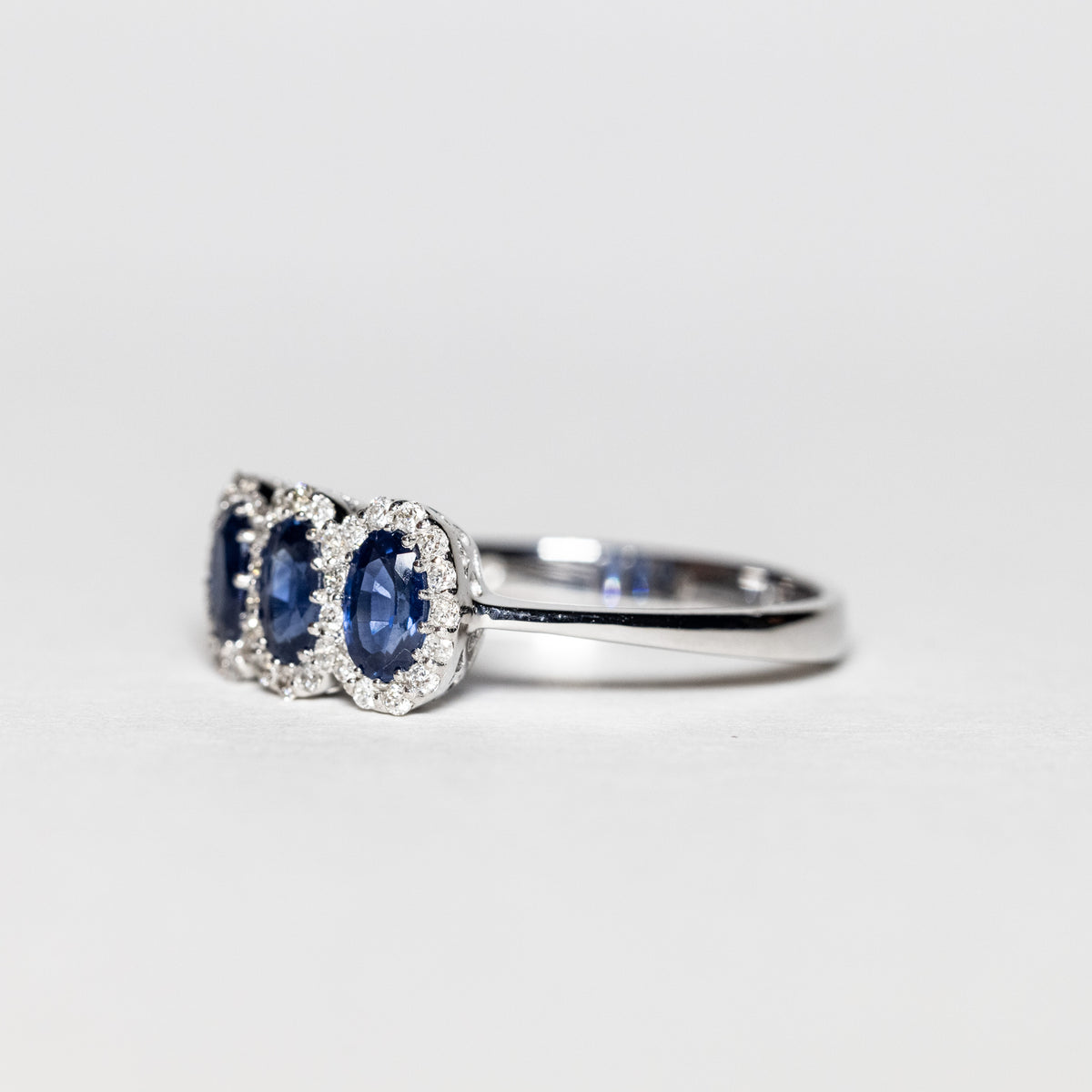 18Kt White Gold Trilogy Ring With Sapphires Surrounded By Diamonds