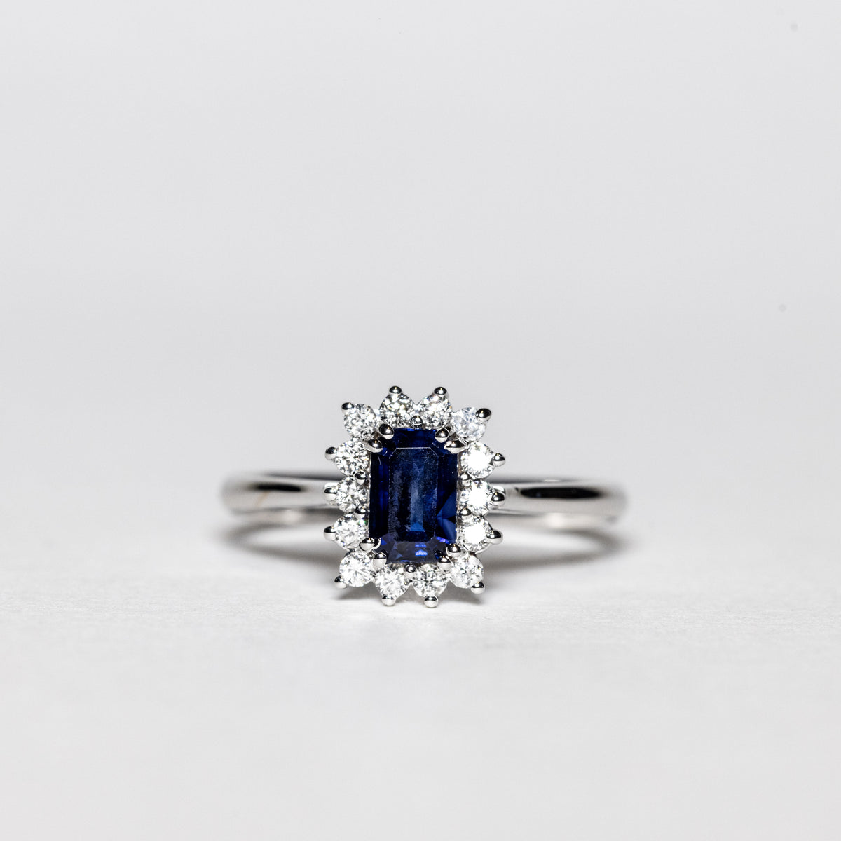 18Kt White Gold Ring with Emerald Cut Sapphire Surrounded by Diamonds