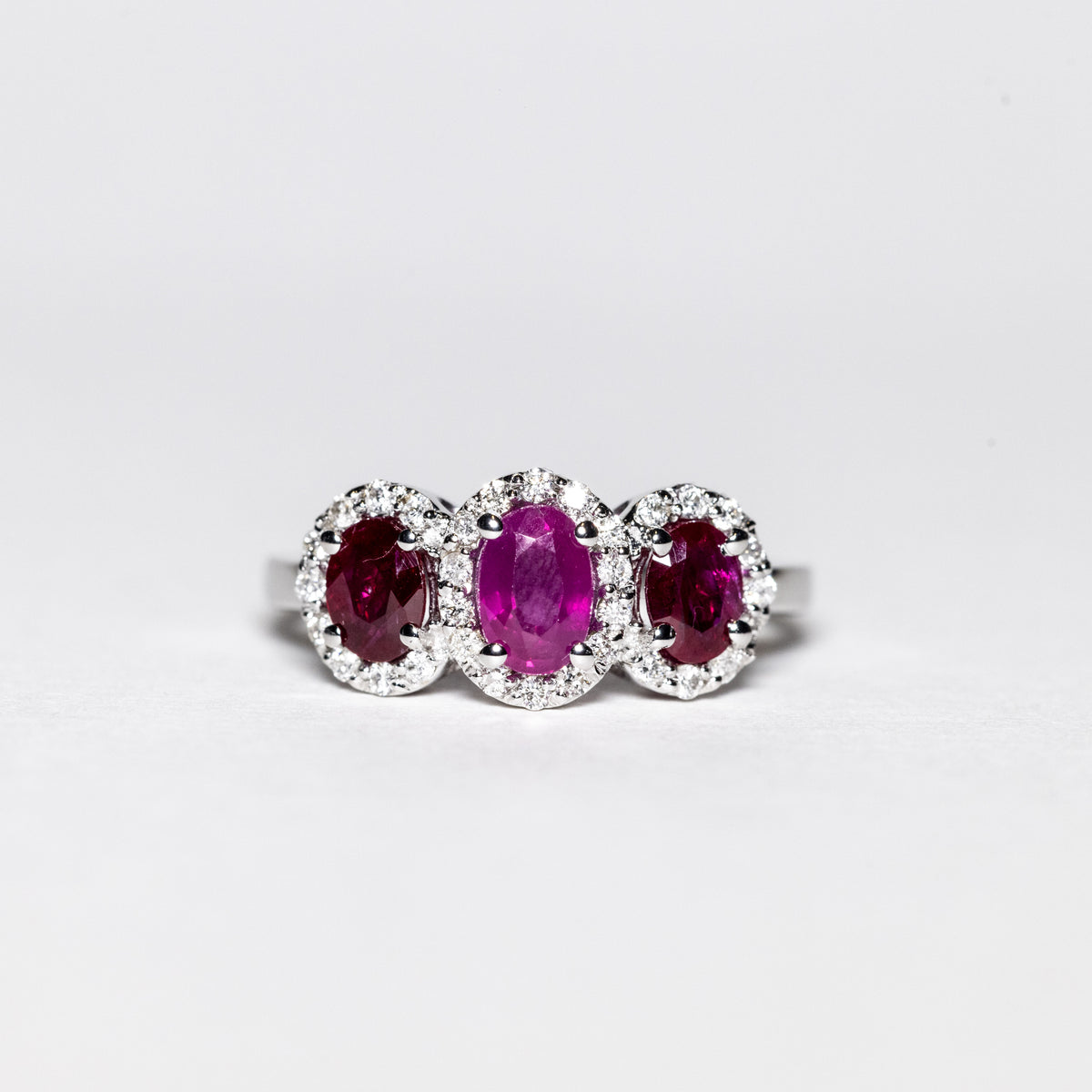 Anello in Oro Bianco 18 Kt con Rubini Laterali Color Rosso e Rubino Centrale Color Rosato Contornati di Diamanti