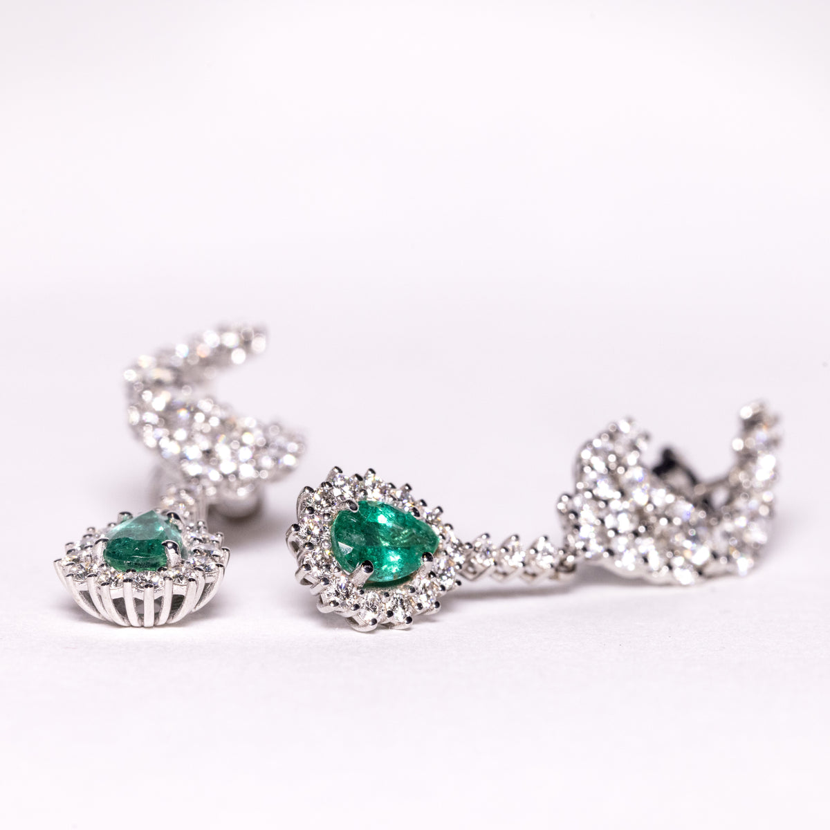 18kt white gold earrings with drop-shaped emeralds surrounded by diamonds
