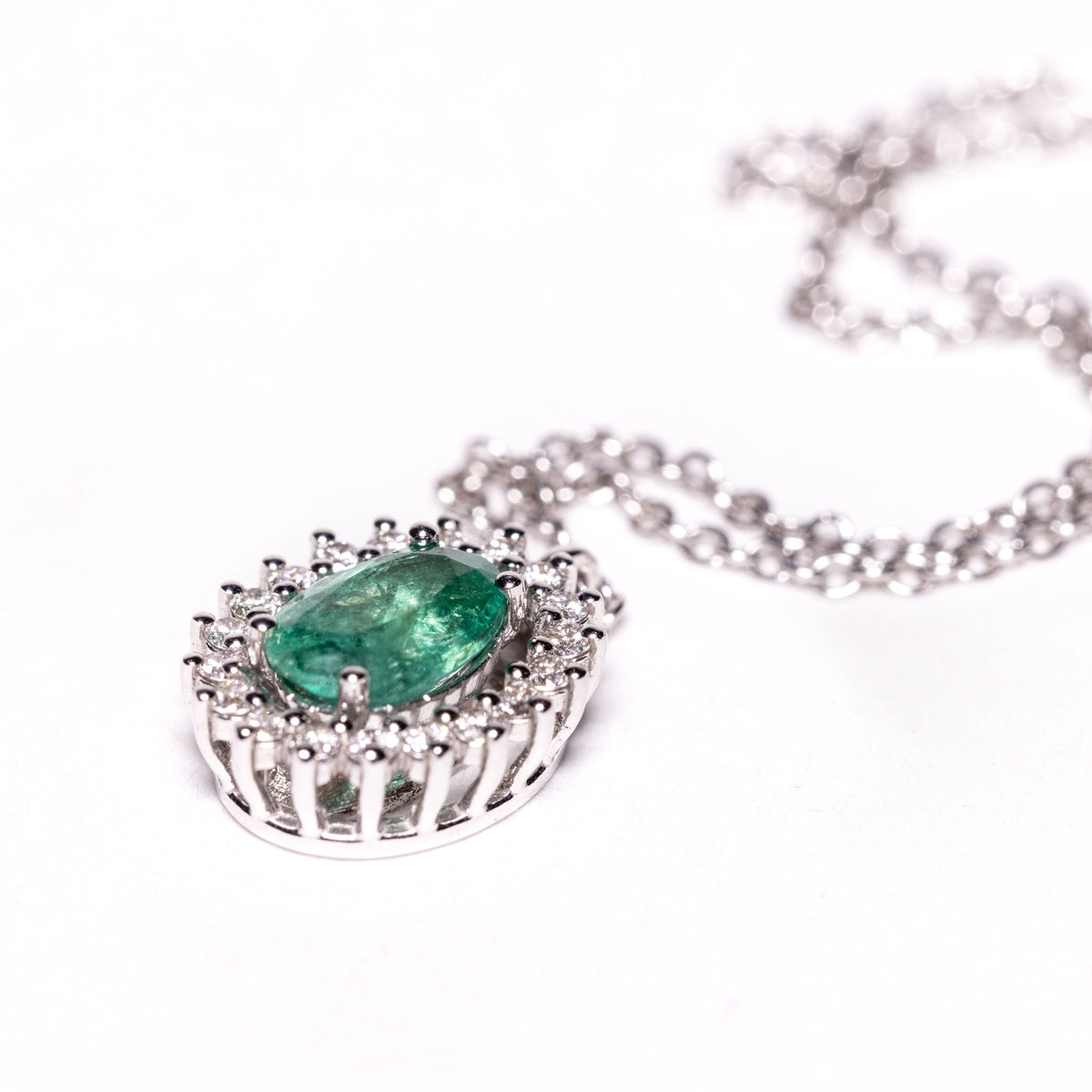 18kt white gold necklace with central emerald surrounded by diamonds. Fancy setting