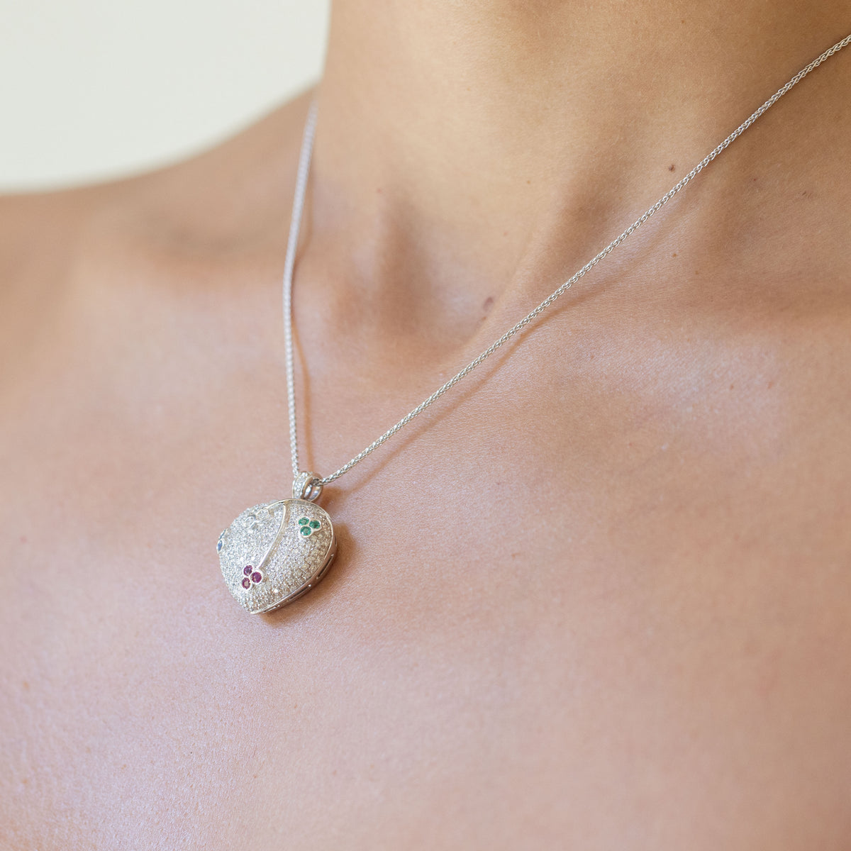 18kt white gold heart-shaped pendant necklace in pavé diamonds and cluster patterns of emeralds, sapphires, rubies and diamonds