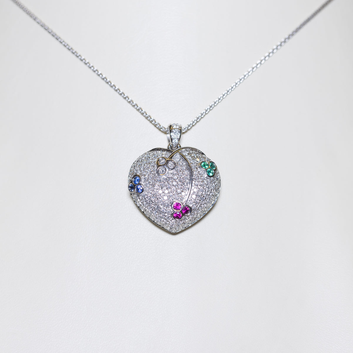 18kt white gold heart-shaped pendant necklace in pavé diamonds and cluster patterns of emeralds, sapphires, rubies and diamonds