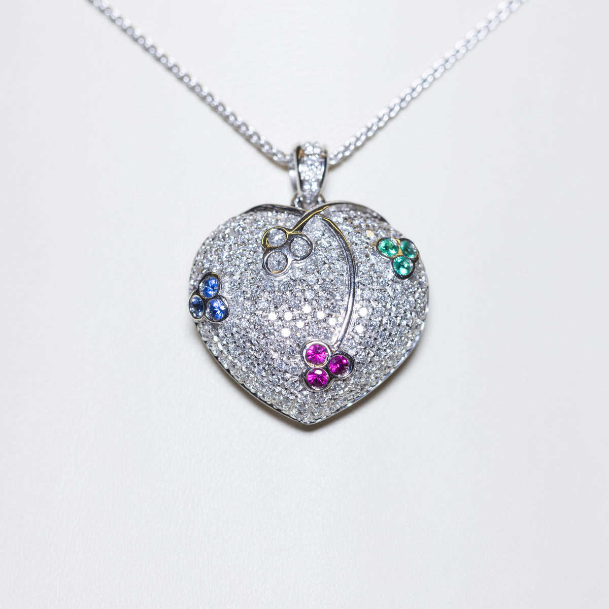 18kt white gold heart-shaped pendant necklace in pavé diamonds and cluster patterns of emeralds, sapphires, rubies and diamonds